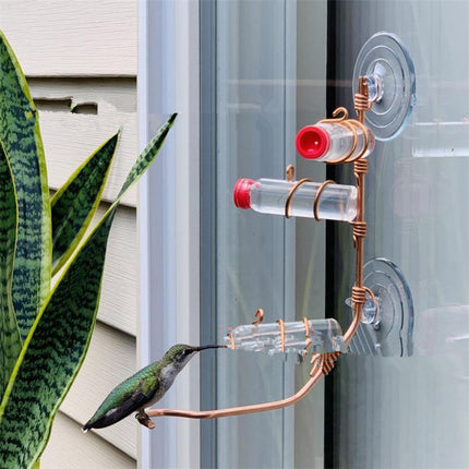 Handmade copper hummingbird feeder with suction cup, transparent PET bottles, and elegant design, perfect for gardens and outdoor spaces.

